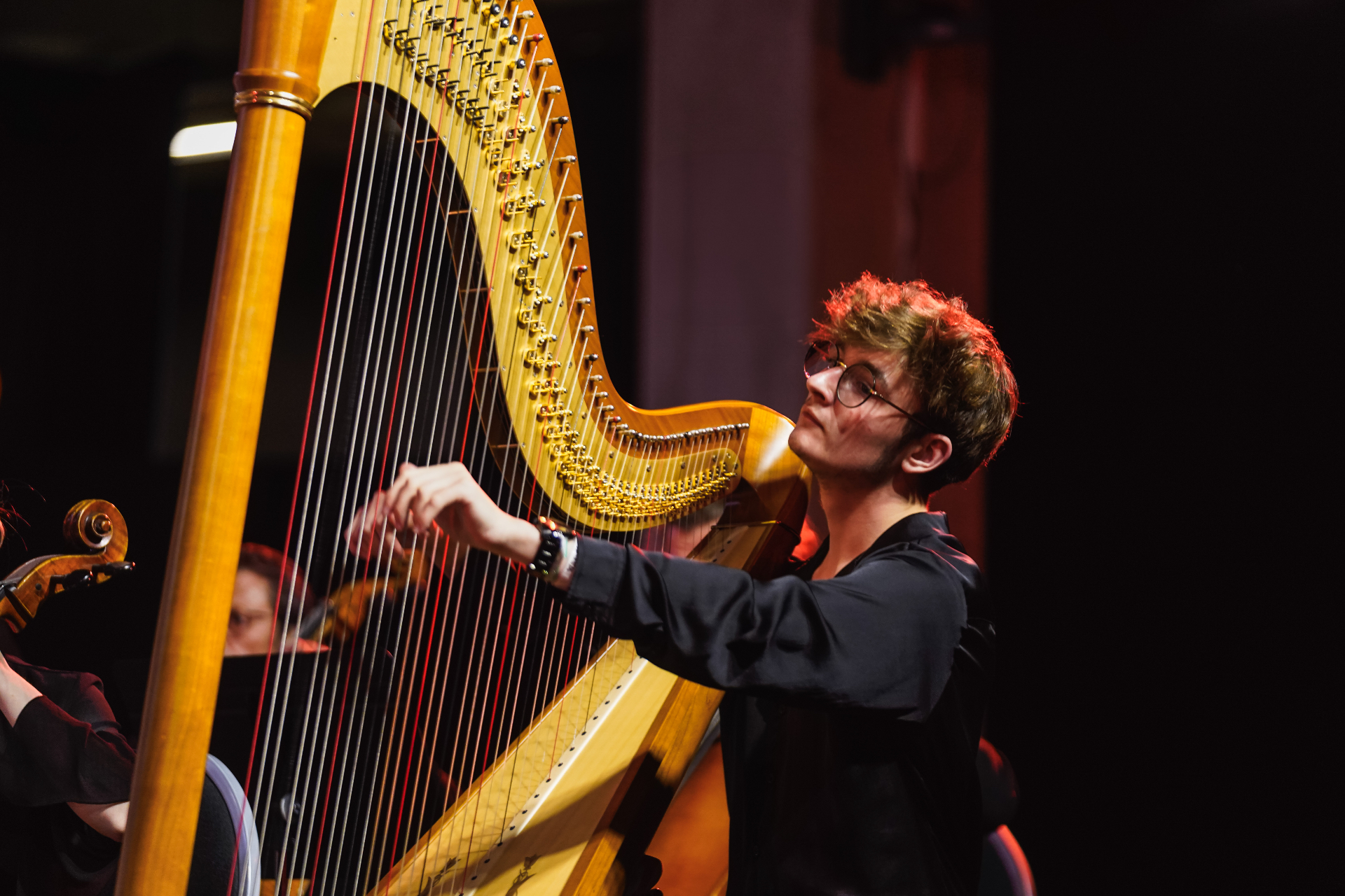 Concert avec orchestre — solo de harpe sous éclairage rouge